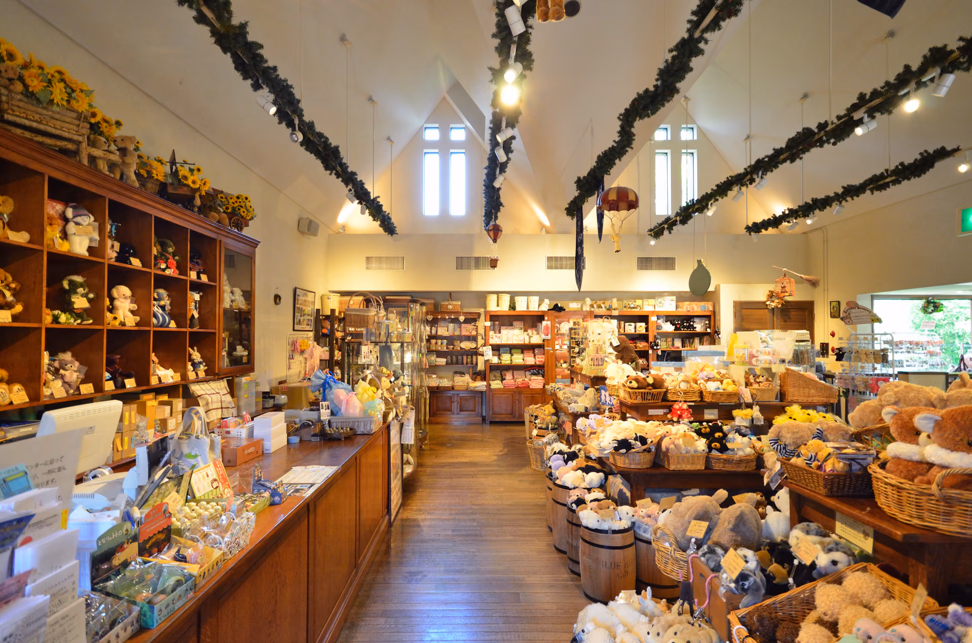 The museum shop under a high white ceiling, with teddy bears in baskets and barrels and wooden shelves of bears and gifts
